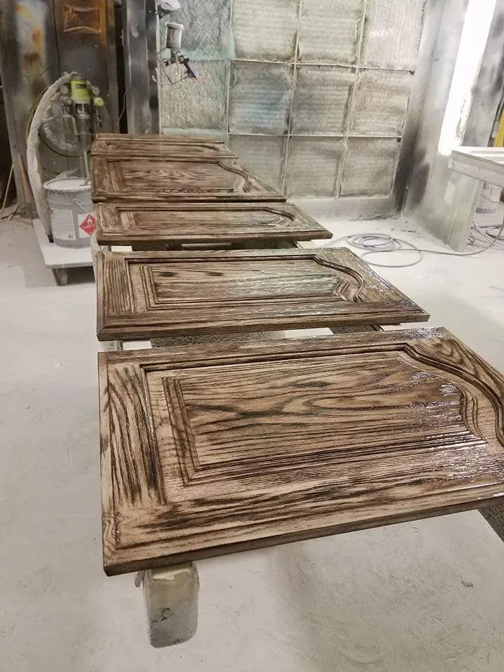 Cabinet doors laid flat on stands in a spray area while the finish dries