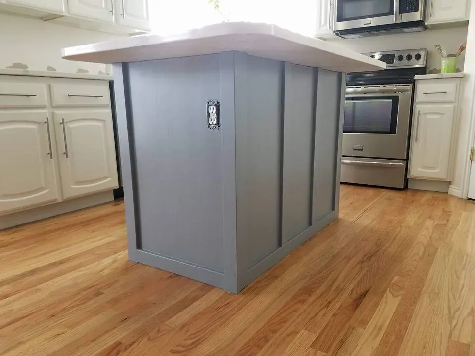 Kitchen island painted slate gray next to white painted perimeter cabinets