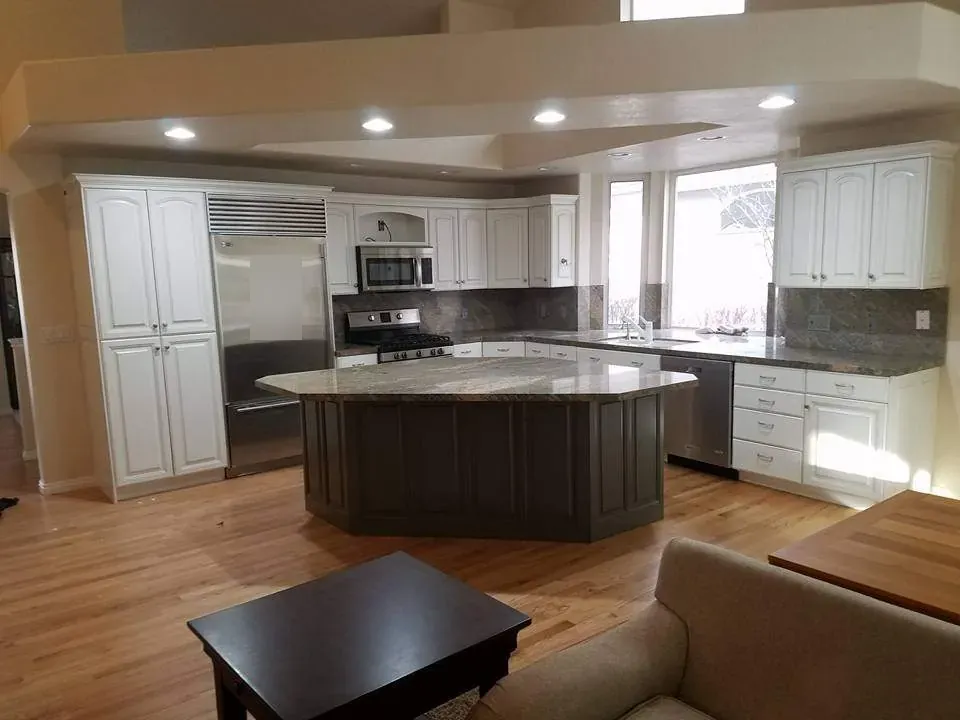 Open kitchen with white painted perimeter cabinets and a dark painted island