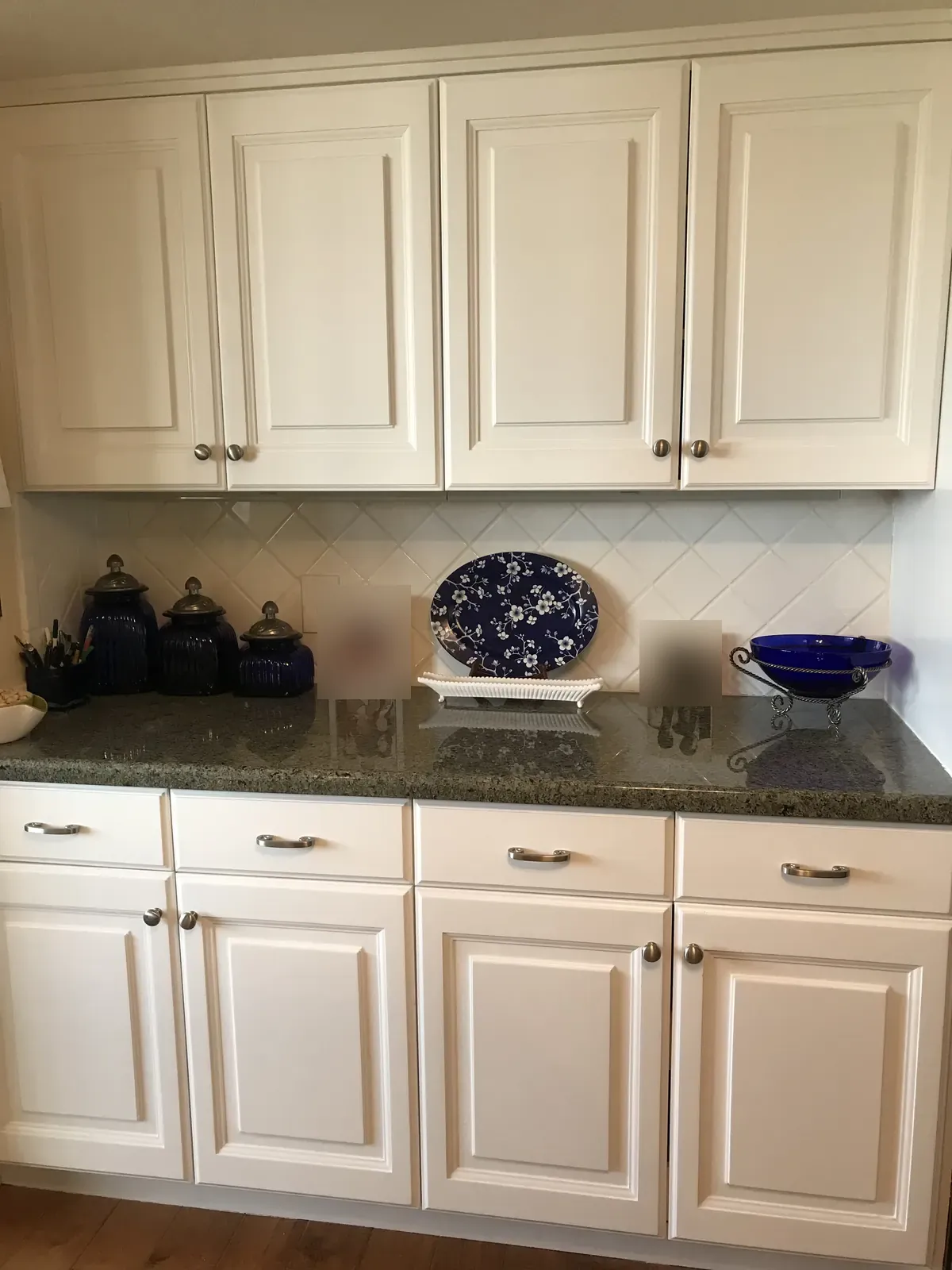 Close-up of white painted raised-panel upper and lower cabinets with granite counters